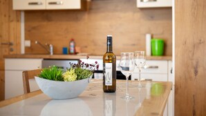 A kitchen with a wooden table, a bottle of wine, two glasses, and a bowl of flowers. - Apartment 'Ferienwohnung Felix' with Balcony and Wi-Fi (Meßstetten)