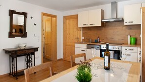 A modern kitchen with wooden cabinets, a dining table with chairs, and a small side table. - Apartment 'Ferienwohnung Felix' with Balcony and Wi-Fi (Meßstetten)