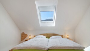 A bedroom with a skylight, a wooden headboard, and a green mattress. - Apartment 'Ferienwohnung Felix' with Balcony and Wi-Fi (Meßstetten)