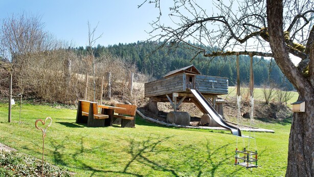 A playground with a slide, swings, and a wooden structure. - Apartment 'Ferienwohnung Felix' with Balcony and Wi-Fi (Meßstetten)