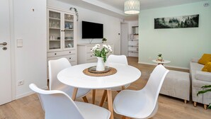 Una sala de estar moderna con comedor, un televisor de pantalla plana y un cuadro en la pared.