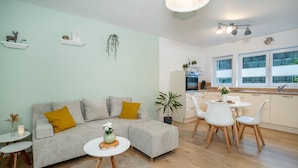 Una sala de estar moderna con un sofá, un reposapiés, una mesa de centro y un comedor con sillas y una mesa.