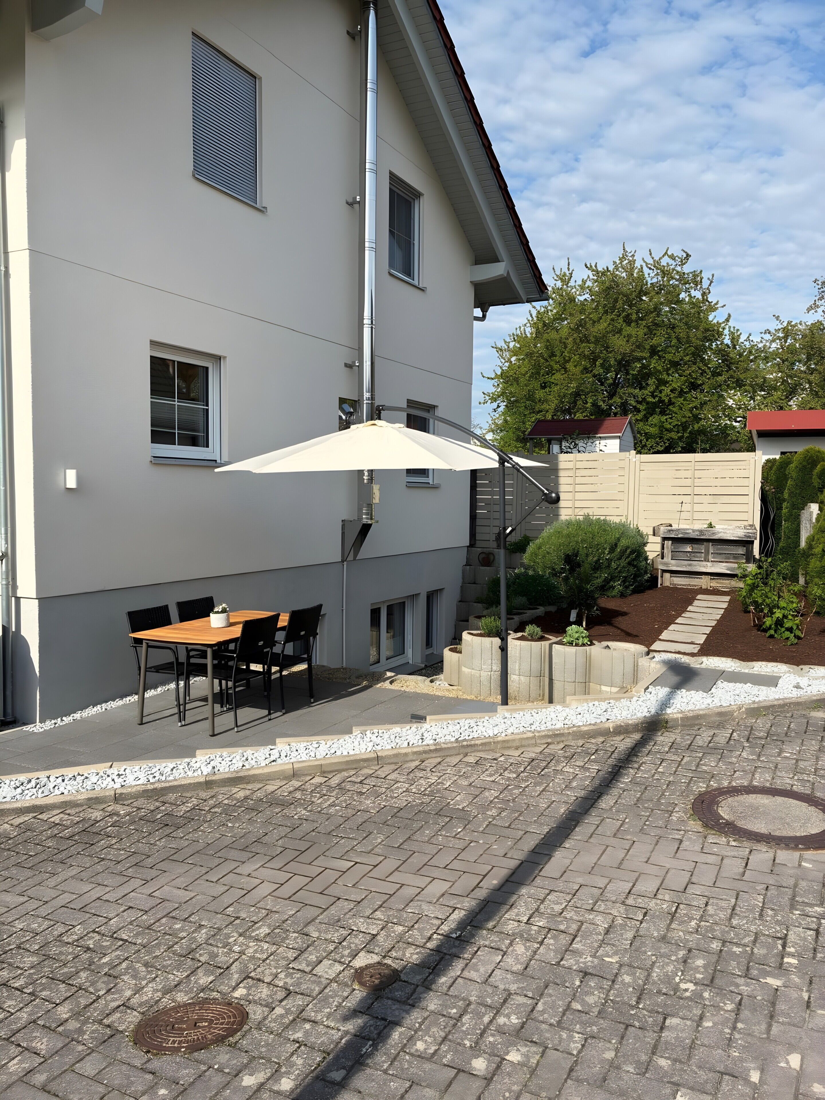 A building with a patio area, outdoor seating, and a garden.