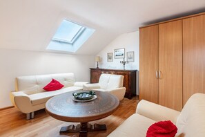 Une pièce dotée d’une lucarne, d’une table ronde en bois, d’un canapé blanc et d’un meuble en bois.