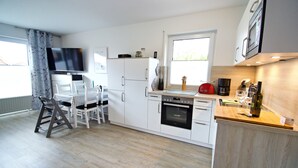 Eine moderne Küche mit weißen Schränken, einem eingebauten Backofen und einer Holz Arbeitsplatte.