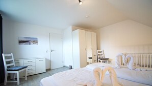 Ein Hotelzimmer mit Bett, Schreibtisch, Stuhl, Kleiderschrank und einem Reisebett.