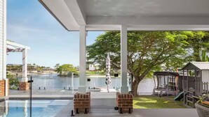 A poolside area with a glass enclosure, a brick structure, and a playground. - Luxury Villas Allambi Broadbeach (With Car Parking) (Broadbeach Waters)