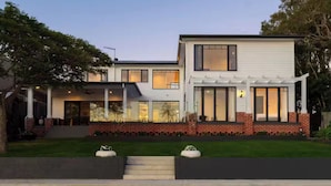A modern two-story house with a covered porch, large windows, and a brick foundation. - Luxury Villas Allambi Broadbeach (With Car Parking) (Broadbeach Waters)