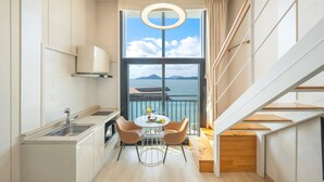 Una cocina moderna con vista al mar, un comedor con dos sillas y una escalera.