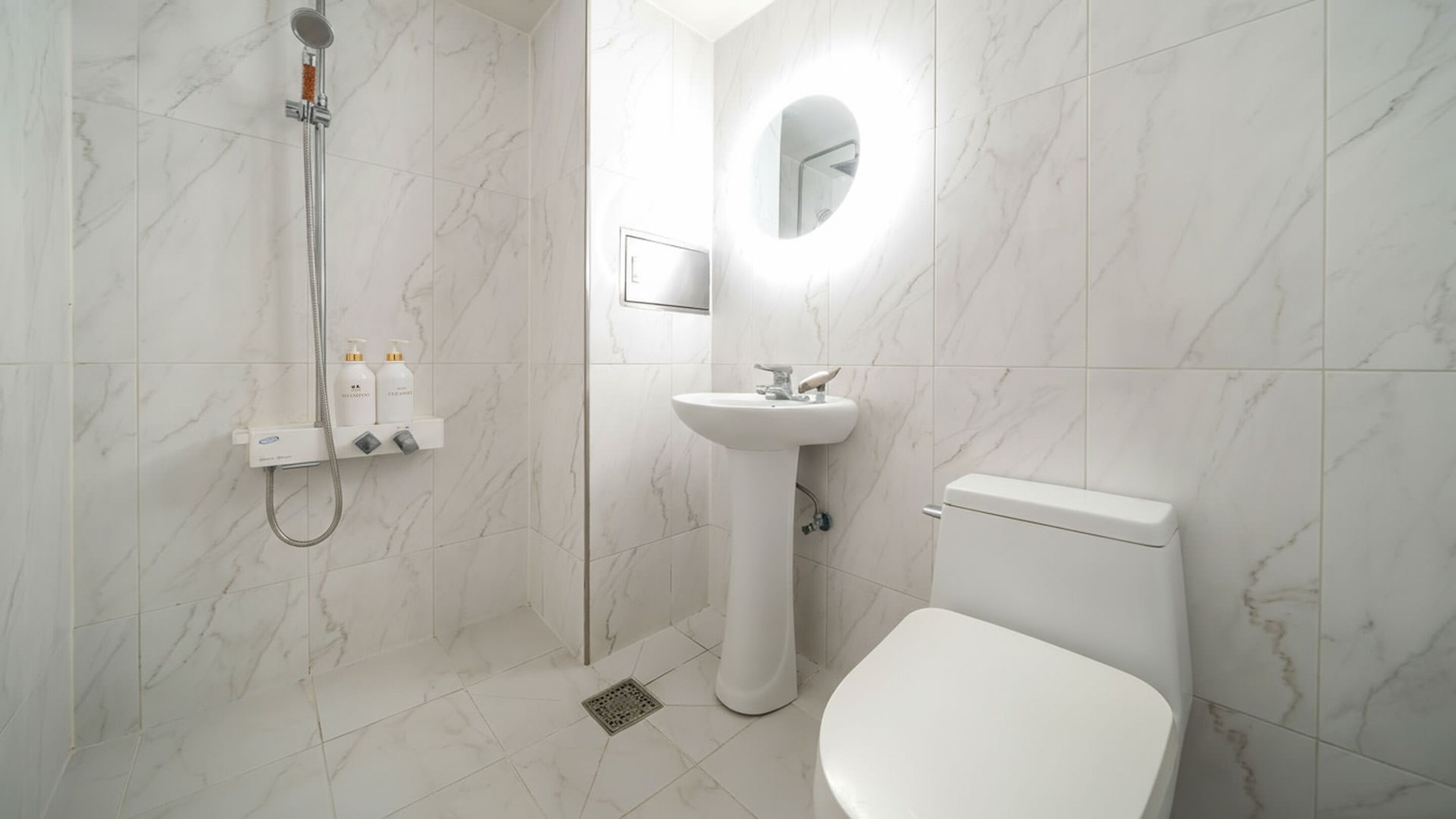 A modern bathroom with a shower, sink, and toilet.