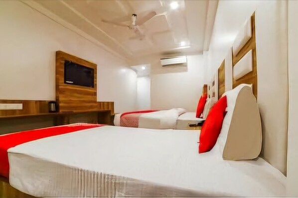 A hotel room with a large bed, a smaller bed, a TV mounted on the wall, and a ceiling fan.