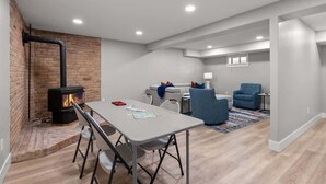 Ein modernes Wohnzimmer mit Kamin, Esstisch und einer Sitzecke mit Sofa und Sesseln.