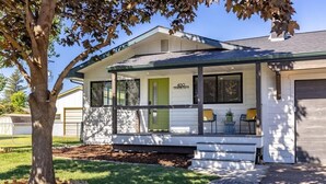 Ein eingeschossiges Haus mit Veranda, einer grünen Tür und einer Garage.