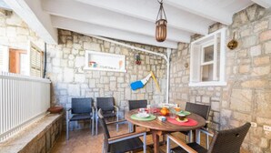 Uma sala de jantar com paredes de pedra, uma mesa redonda, cadeiras e um lustre.