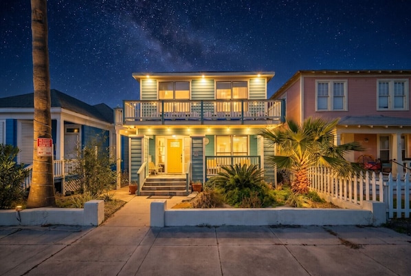 A two-story house with a balcony, a front porch, and a well-lit entrance.