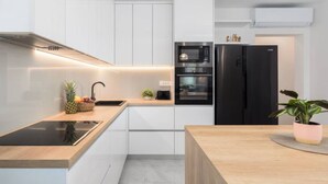 Eine moderne Küche mit weißen Schränken, einem schwarzen Kühlschrank, einem eingebauten Backofen und einer Holz Arbeitsplatte.