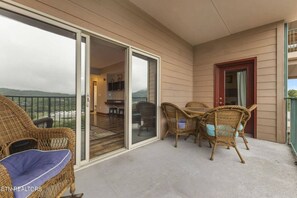 Ein Balkon mit Korbmöbeln, eine Schiebetür zu einem Essbereich und Blick auf die Landschaft.