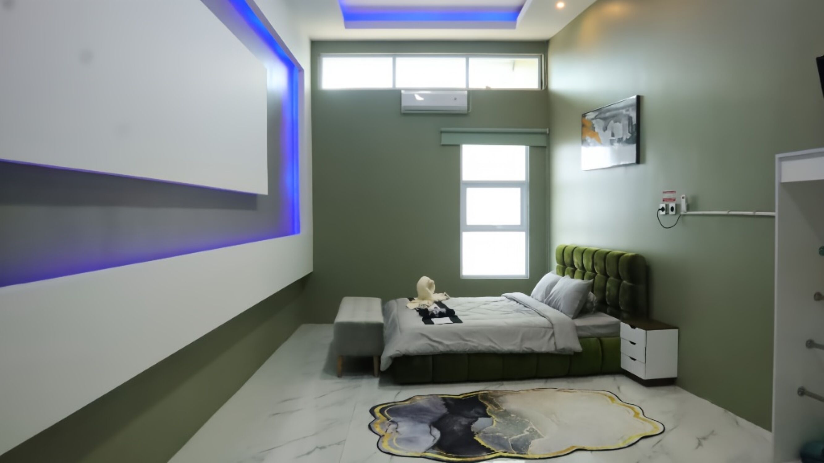 Quarto moderno com cama, mesas de cabeceira, uma janela e um tapete de chão único.