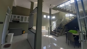 A spacious, modern interior with a kitchen, dining area, and a staircase leading to an upper level. - DeBali Villa Countryside by Simply Homy (Banyuresmi)