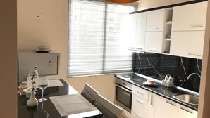 A modern kitchen with a black countertop, white cabinets, and a black and white marble backsplash. - SUNLIT ERISI’s HOUSE - City center (Tiranë)