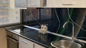 A kitchen with a black countertop, stainless steel sink, and a backsplash with a crackled pattern. - SUNLIT ERISI’s HOUSE - City center (Tiranë)