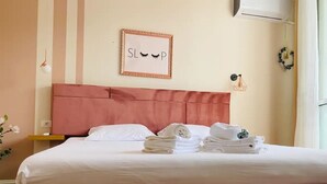 A neatly made bed with white linens and towels, a pink headboard, and a framed sign on the wall. - SUNLIT ERISI’s HOUSE - City center (Tiranë)