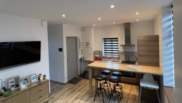 Una cocina moderna con una isla central, taburetes de bar y un televisor de pantalla plana montado en la pared.