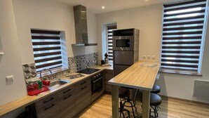 Una cocina moderna con una isla central, electrodomésticos integrados y una ventana con persianas.
