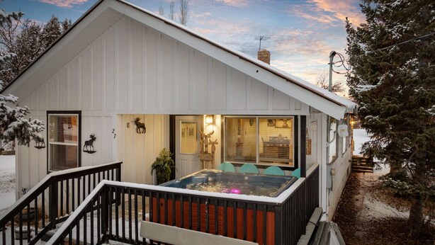 Una casa moderna con jacuzzi en el porche, una escalera y un paisaje nevado.