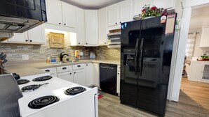 Una cocina moderna con armarios blancos, un refrigerador negro, una estufa y un lavavajillas.
