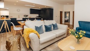 A modern living room with a sofa, a coffee table, and a dining area with a table and chairs. - Cart Shed 2 - From 140 Per Night (Oxford)