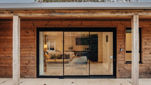 A modern building with a wooden facade and large glass doors leading to an interior with a living area and kitchen. - Cart Shed 2 - From 140 Per Night (Oxford)