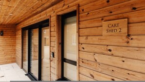 A wooden cabin interior with a sign reading "CART SHED 2" and a door leading to another room. - Cart Shed 2 - From 140 Per Night (Oxford)