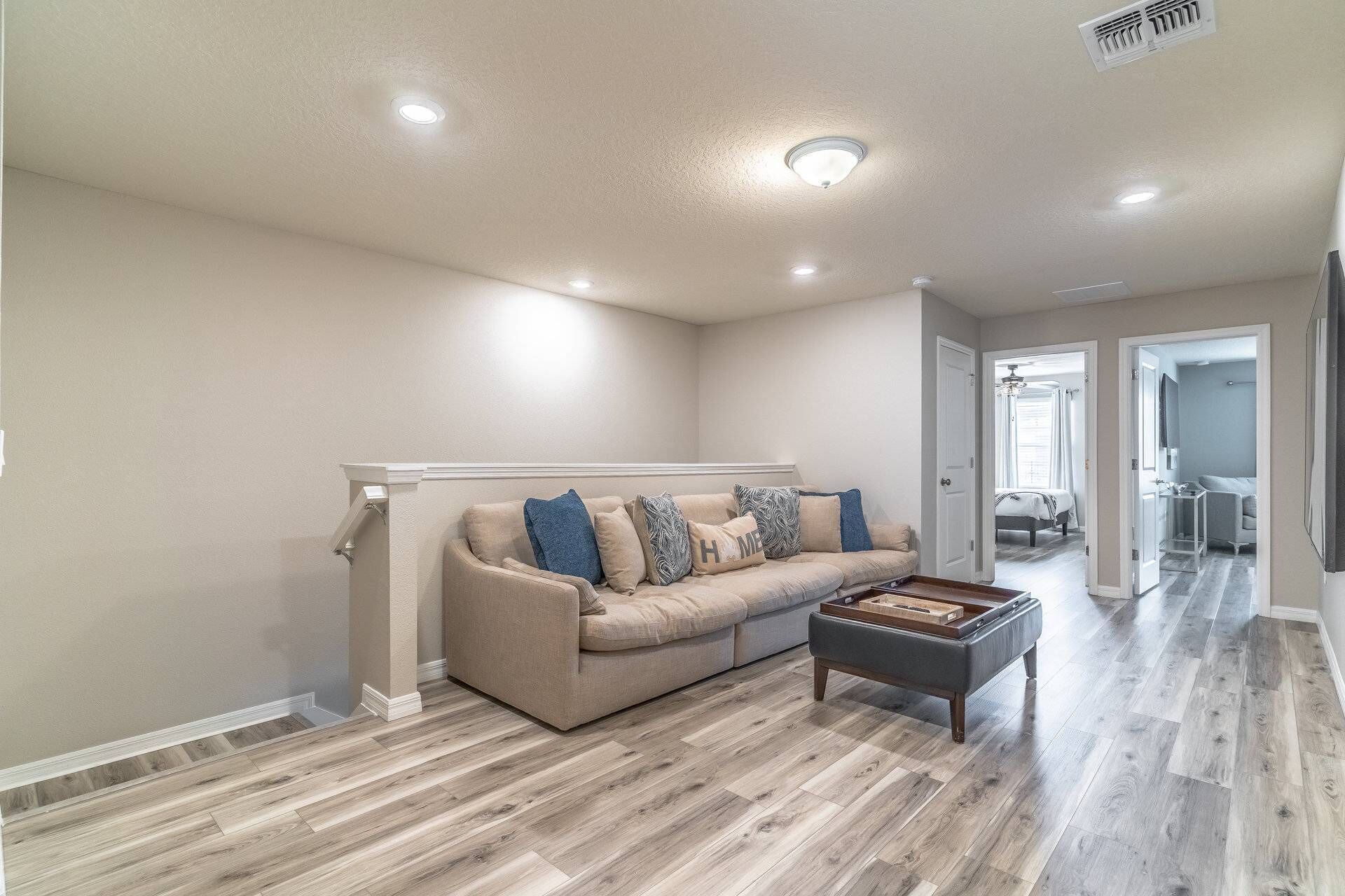 Un salon spacieux avec un canapé beige, une table basse et un plancher en bois.