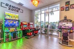Uma área de jogos com máquinas de fliperama, uma janela grande com vista para palmeiras e uma exposição temática de 'TERMINATOR'.
