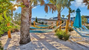 A sandy beach area with hammocks and a blue umbrella.