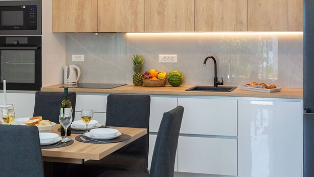 A modern kitchen with wooden cabinets, a built-in microwave, and a dining area with a table set for two.