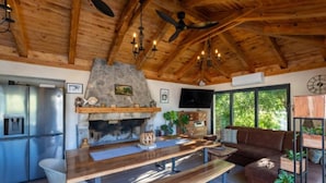 Una cocina rústica con chimenea de piedra, vigas de madera en el techo y un ventanal grande.
