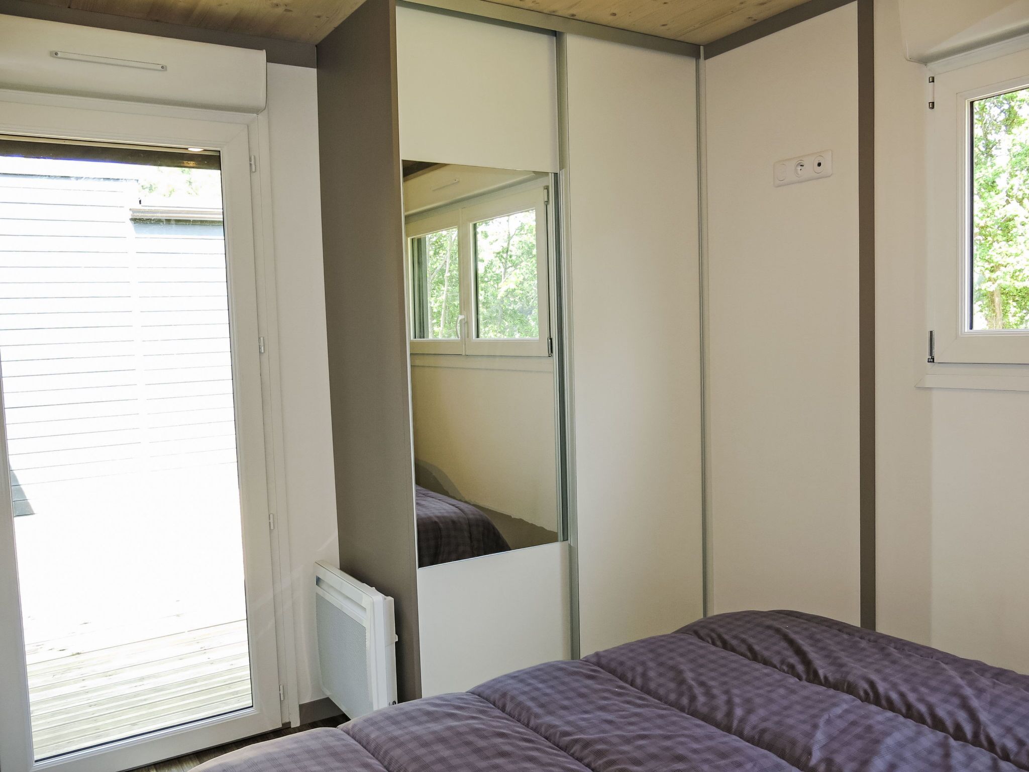 A bedroom with a bed, a window, and a door.