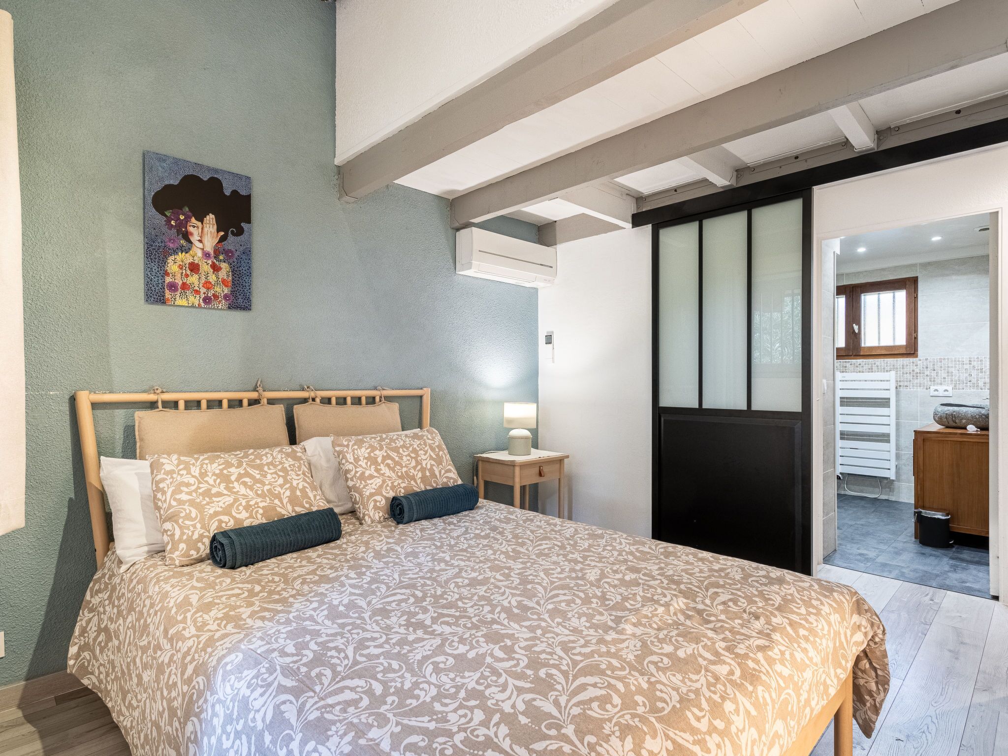 Une chambre à coucher avec un grand lit, une table de chevet avec une lampe et un tableau au mur.