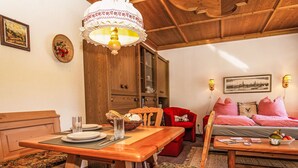 A cozy room with a wooden dining table, a red armchair, a sofa with checkered cushions, and a chandelier. - Dachstein Top 12 by Interhome (Flachau)