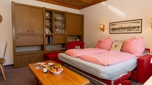 A cozy room with a bed, a wooden cabinet, a table with fruit, and a painting on the wall. - Dachstein Top 12 by Interhome (Flachau)