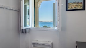 A room with a window overlooking a coastal view, a radiator, and a framed picture on the wall. - Le Provençal by Interhome (Le Pradet)