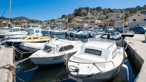 A marina with various boats docked, surrounded by residential buildings and hills in the background. - Le Provençal by Interhome (Le Pradet)