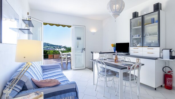 Una habitación moderna y bien iluminada con sofá, mesa de comedor y zona de cocina.