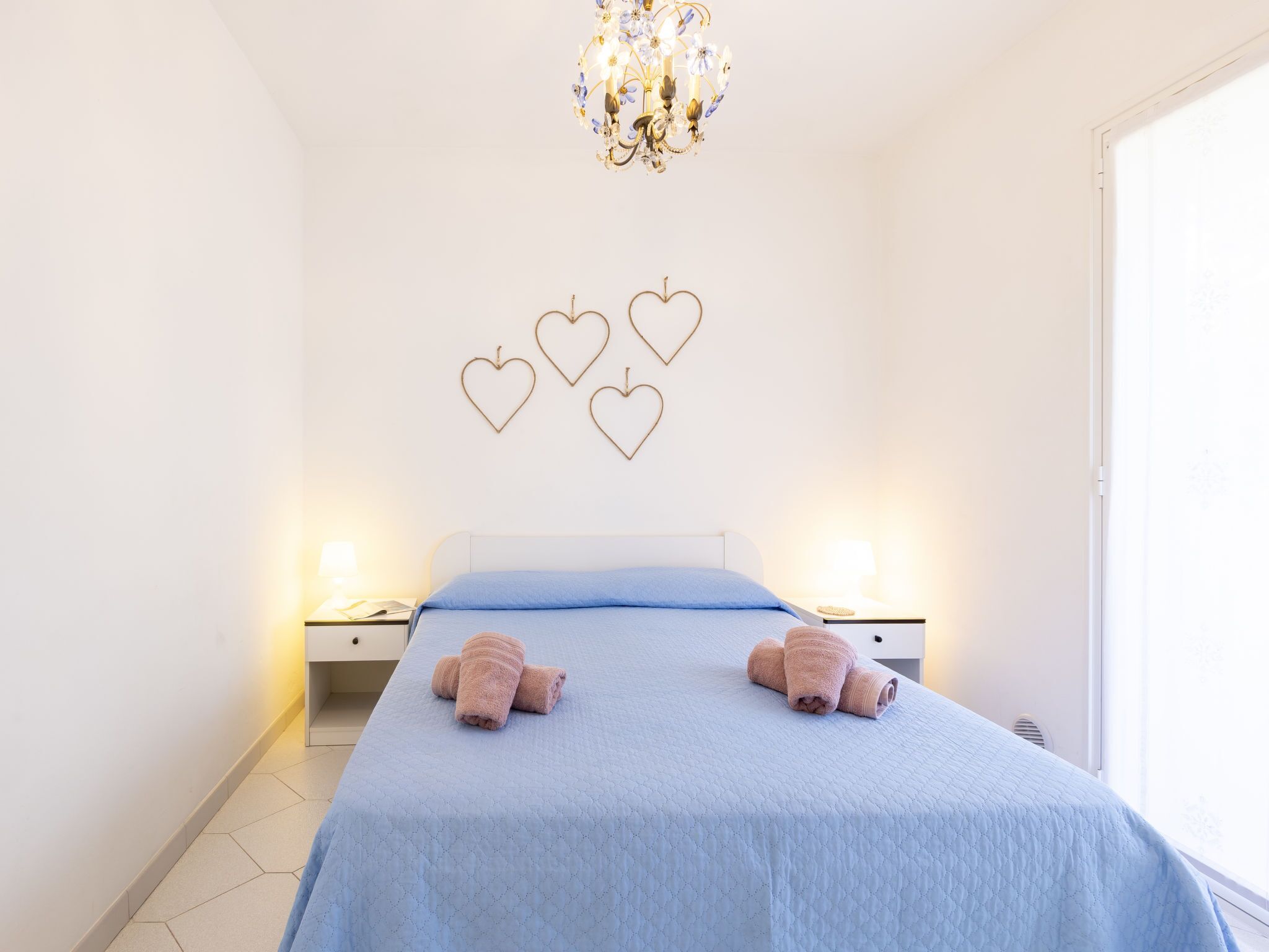 Une chambre à coucher avec un lit, deux tables de chevet, un lustre et des décorations murales en forme de cœur.