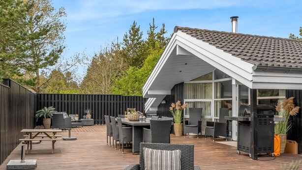 A deck with outdoor furniture, a grill, and a covered area with windows.