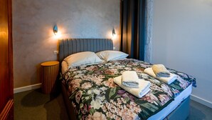A hotel room with a bed, two wall-mounted lights, a round side table, and a curtain. - Seaside Escape Rovinj Old Town Apartment (Rovinj)