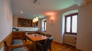 A dining area with a wooden table and chairs, a kitchen in the background, and a window with a view. - Seaside Escape Rovinj Old Town Apartment (Rovinj)