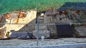 A stone terrace with outdoor seating and a railing overlooking clear water. - Seaside Escape Rovinj Old Town Apartment (Rovinj)
